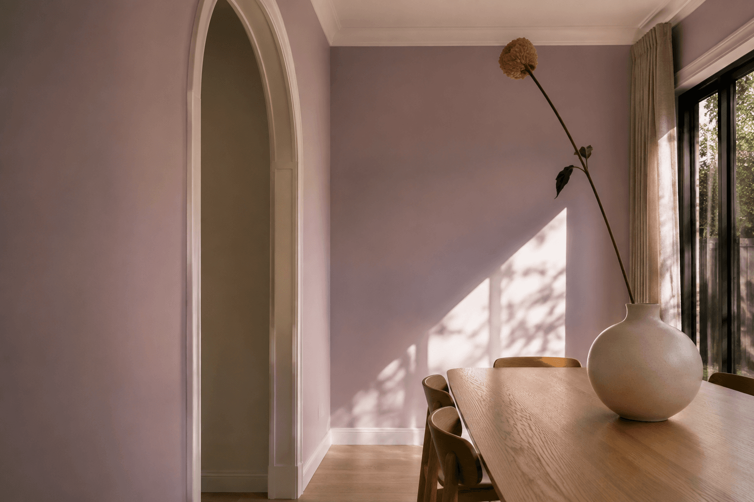 Lilac dining room with a painted arched doorway and warm timber furniture